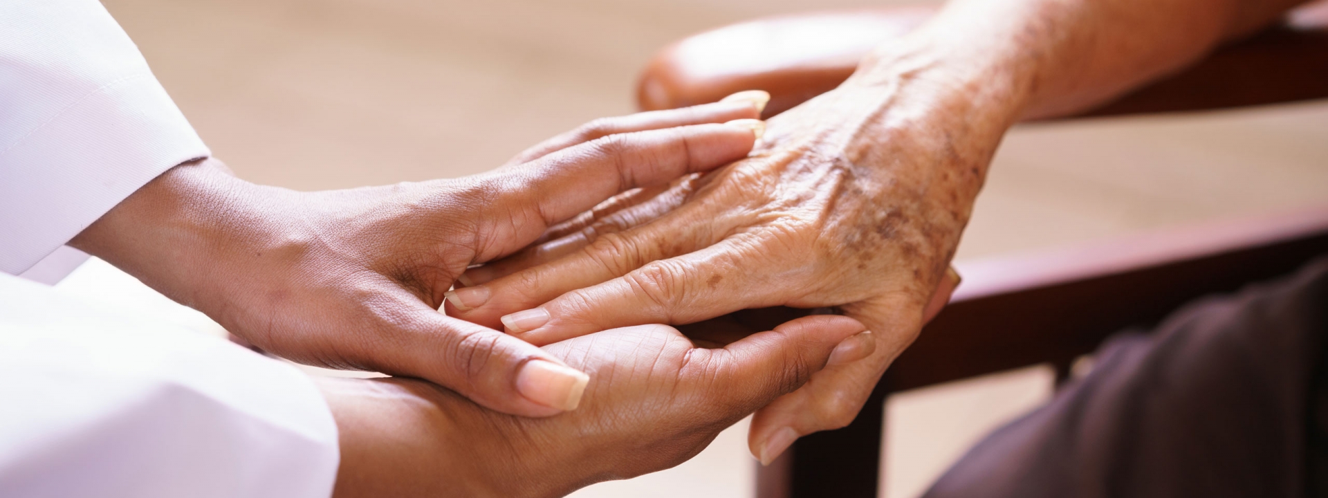 Caregiver and senior holding hands.